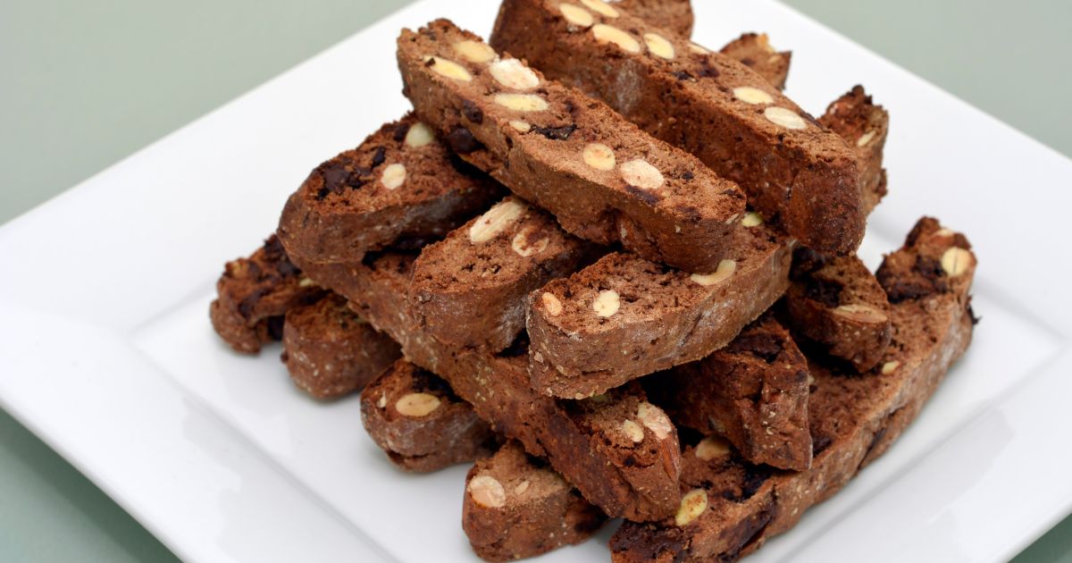 Chocolate almond biscotti stacked on a white plate.