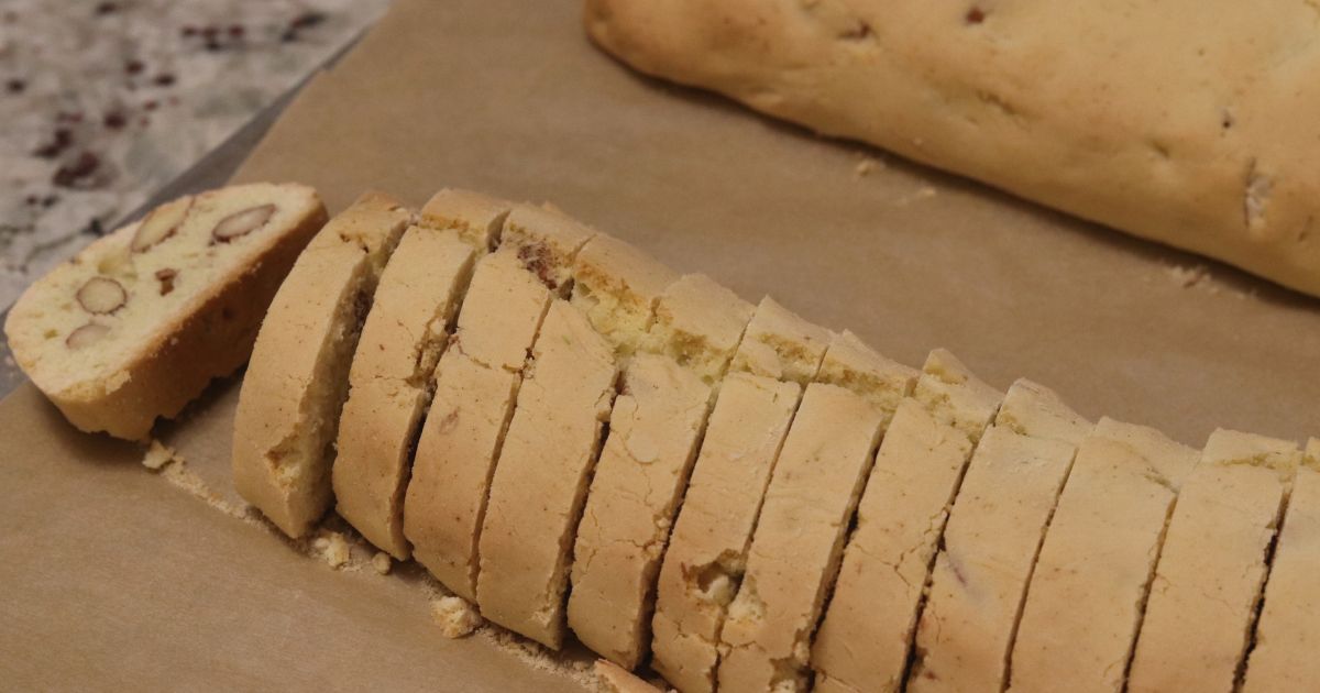 Slicing a warm log of biscotti dough before the second bake.