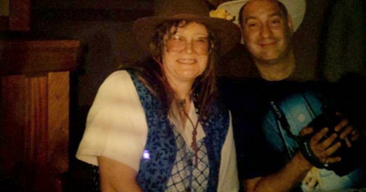 The author’s mother smiling in a brown wide-brimmed hat, glasses and a blue patterned vest, beside the author’s stepdad in a white hat.